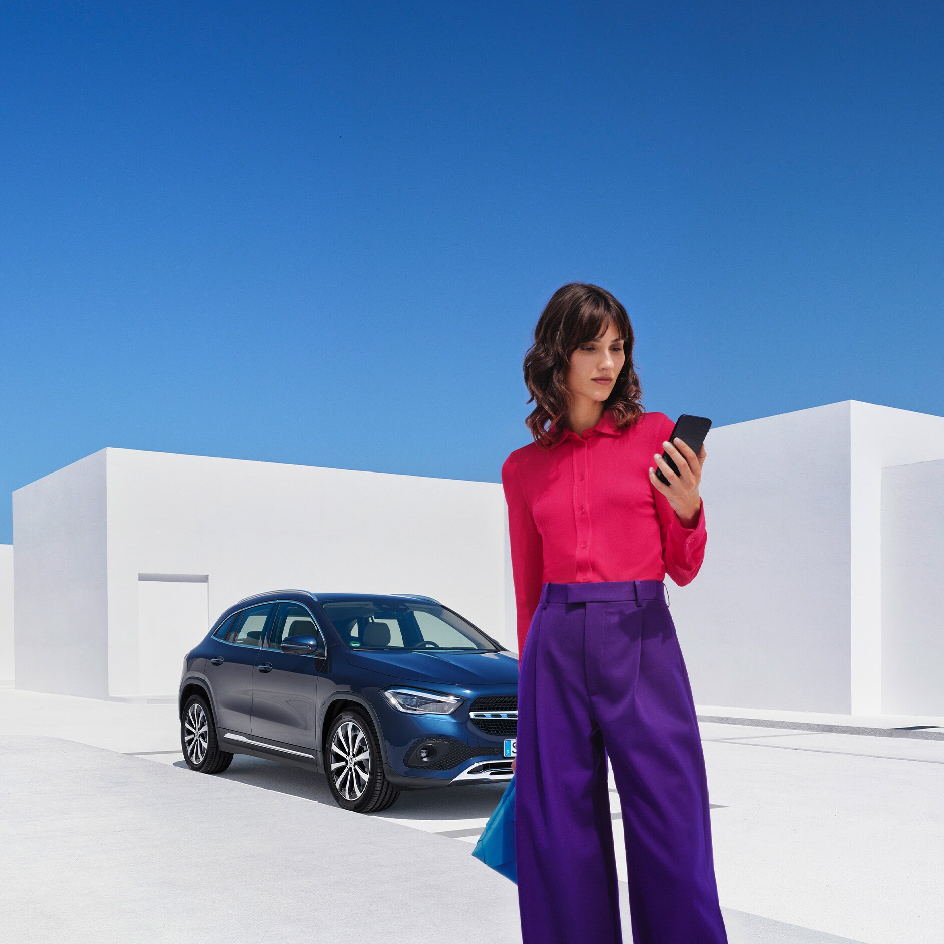 Zo werkt het | Apps | Mercedes me Een vrouw brengt via de Mercedes Me app op haar smartphone een verbinding met haar Mercedes-Benz tot stand.