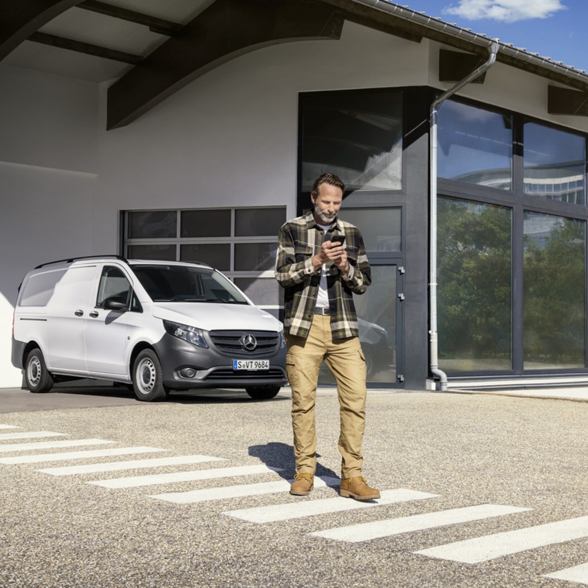 Mercedes-Benz Store | Digitaal extra | Mercedes-Benz Een persoon met een smartphone voor een Mercedes-Benz Vito.